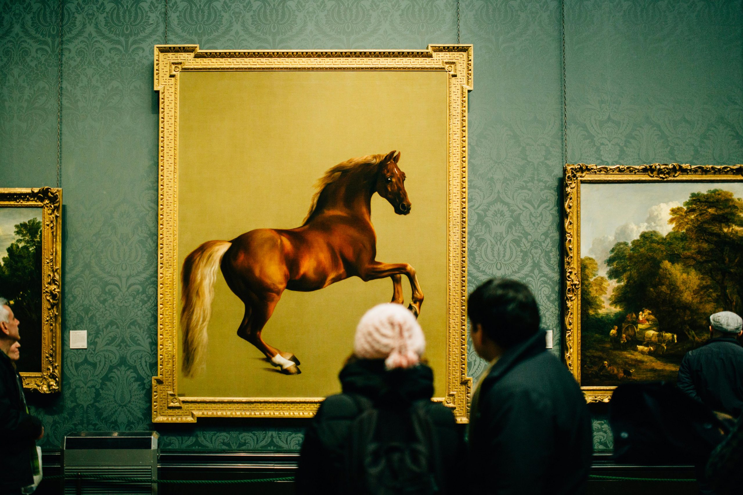 Visitors view a majestic horse painting at a museum, showcasing art appreciation and cultural exploration.