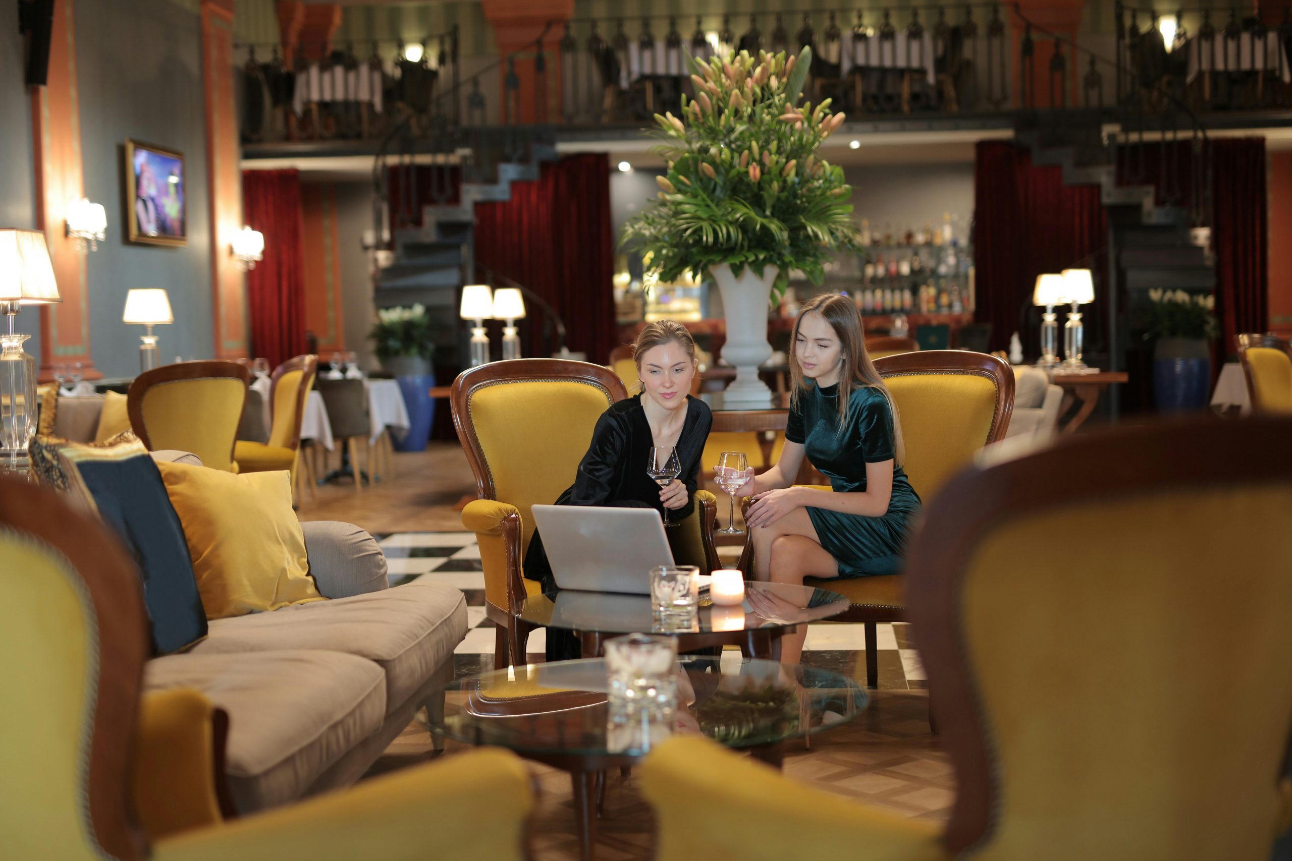 Two women enjoying a conversation in a luxurious hotel lounge, surrounded by elegant decor.